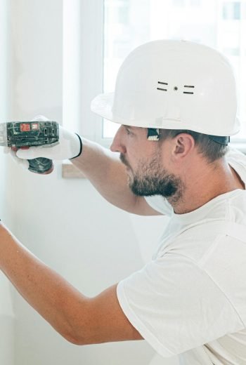 Carpenter skillfully uses a drill wearing safety gear during a renovation project indoors.