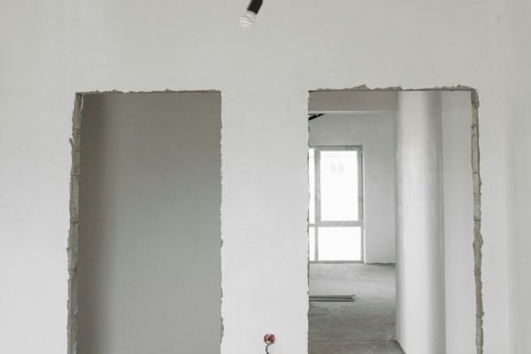Unfinished room interior with white plastered walls and exposed ceiling in a construction site.